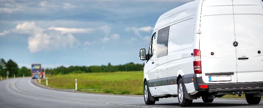 white van driving on country road