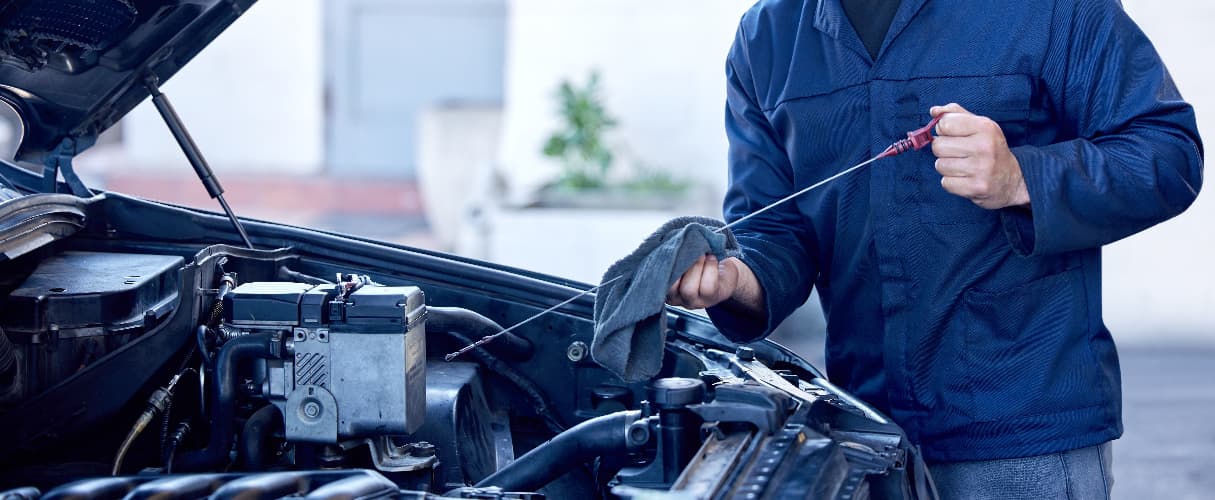 man wiping engine dipstick to check engine oil