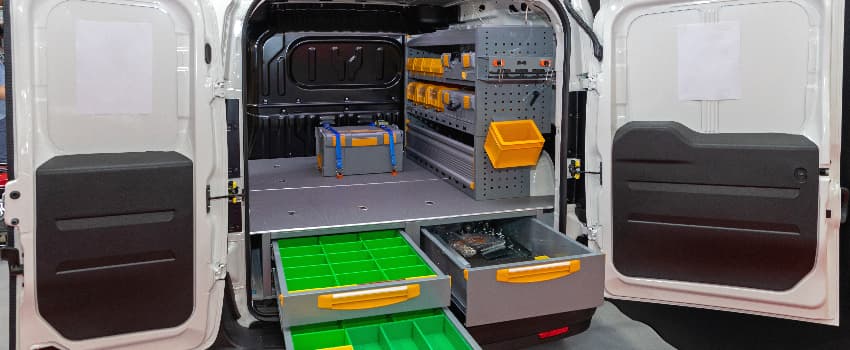 Rear view of a van conversion with built-in shelving, tool storage, drawers and organised compartments for work equipment